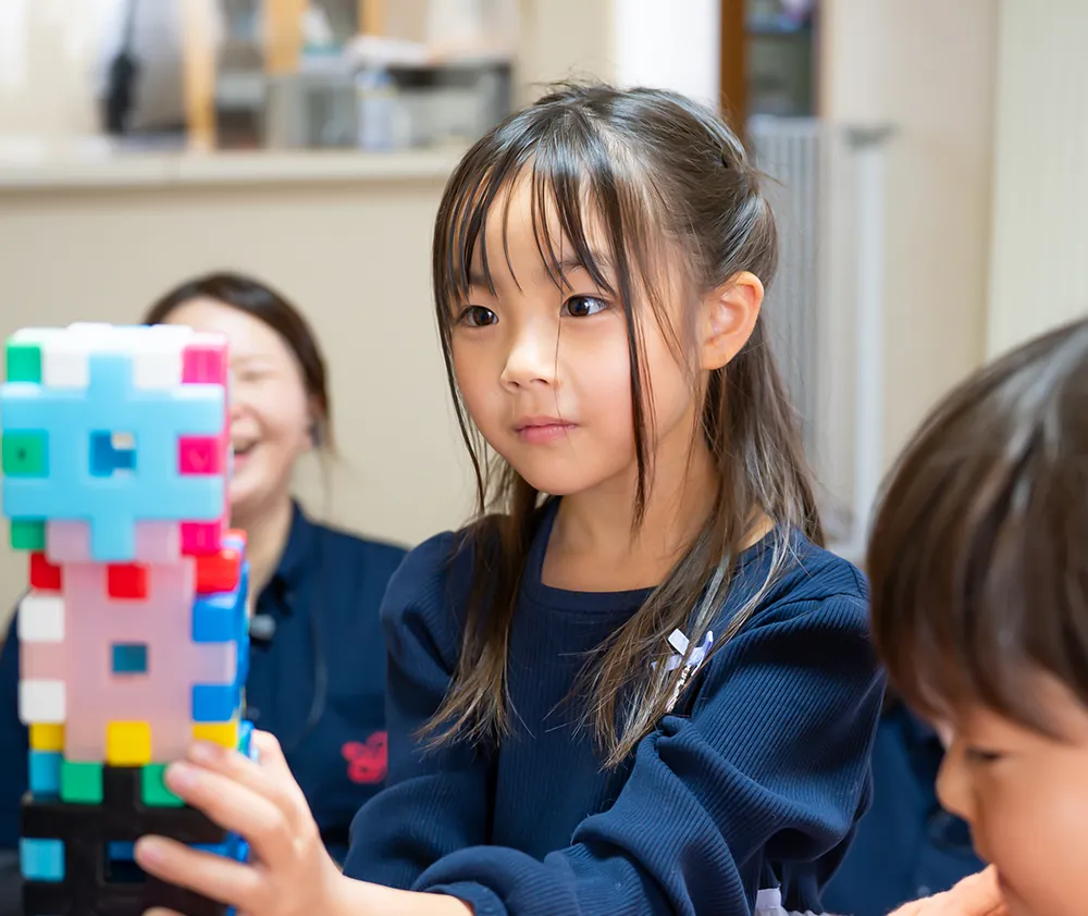 カラフルなブロックを真剣に見つめて組み立てる女の子