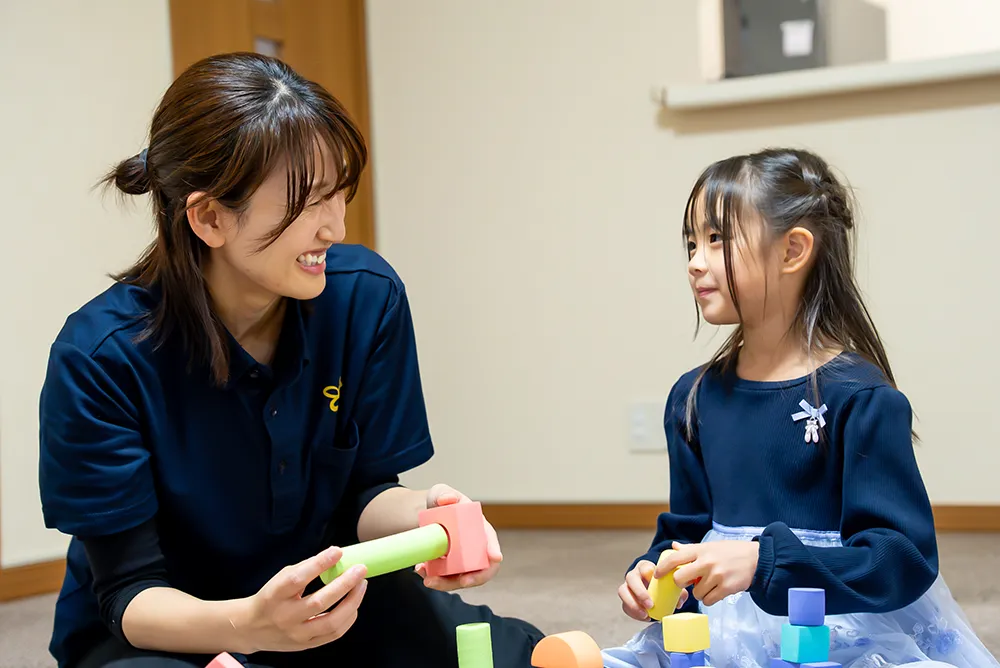女性スタッフが子どもの表情を見ながら笑顔で関わる様子
